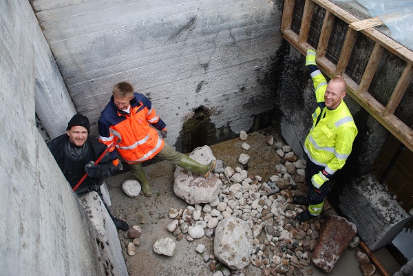 Omgjøring av laksetrapp til hartrapp ved Høyegga i Glomma. Ved hjelp av kranbil fylles trappa med grus og grøvre stein. Ulrich Pulg (Uni Miljø), Trond Taugbøl (GLB) og Runar Rueslåtten (Eidsiva Vannkraft) danderer stein og grus på bunnen av trappa slik at strømningsforholdene skal bli best mulig for fisken. Foto: Jon Museth